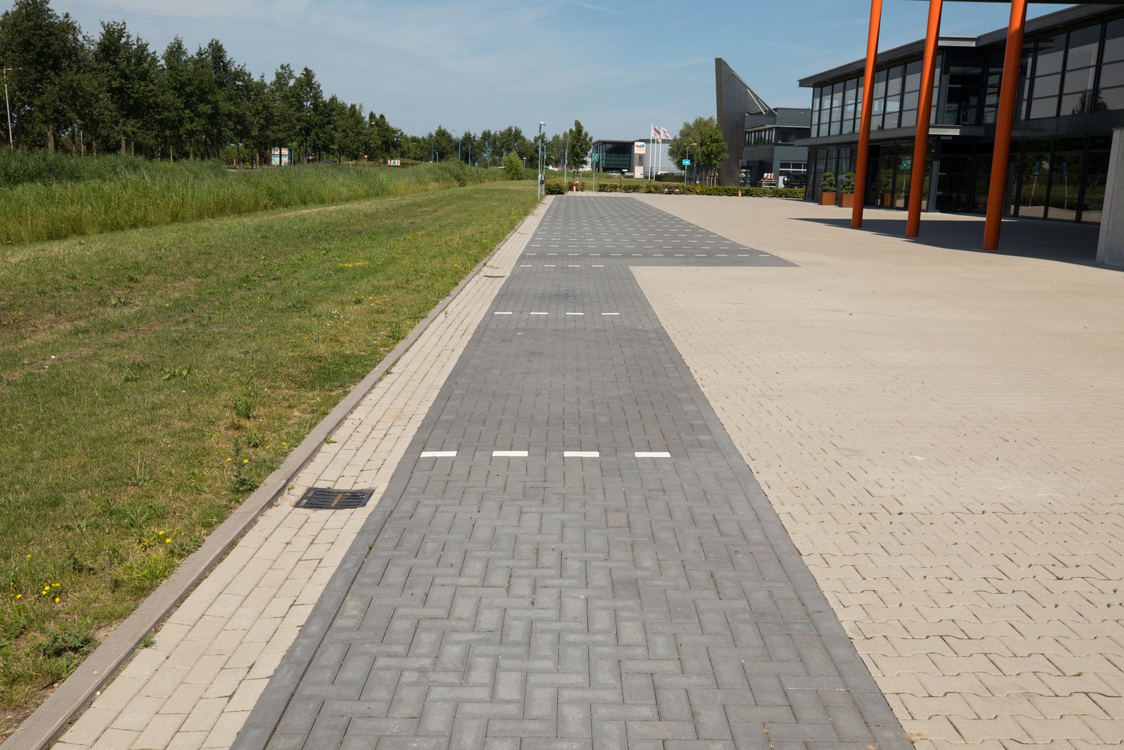 Entreezone met bestraat pad langs de gevel en oranje gevelaccenten