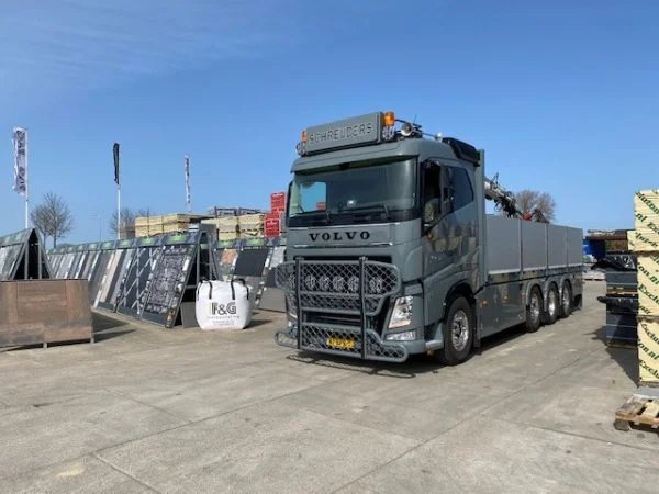 Kraanwagen geladen met bestrating op het terrein van F&G, naast een big bag met het F&G-logo