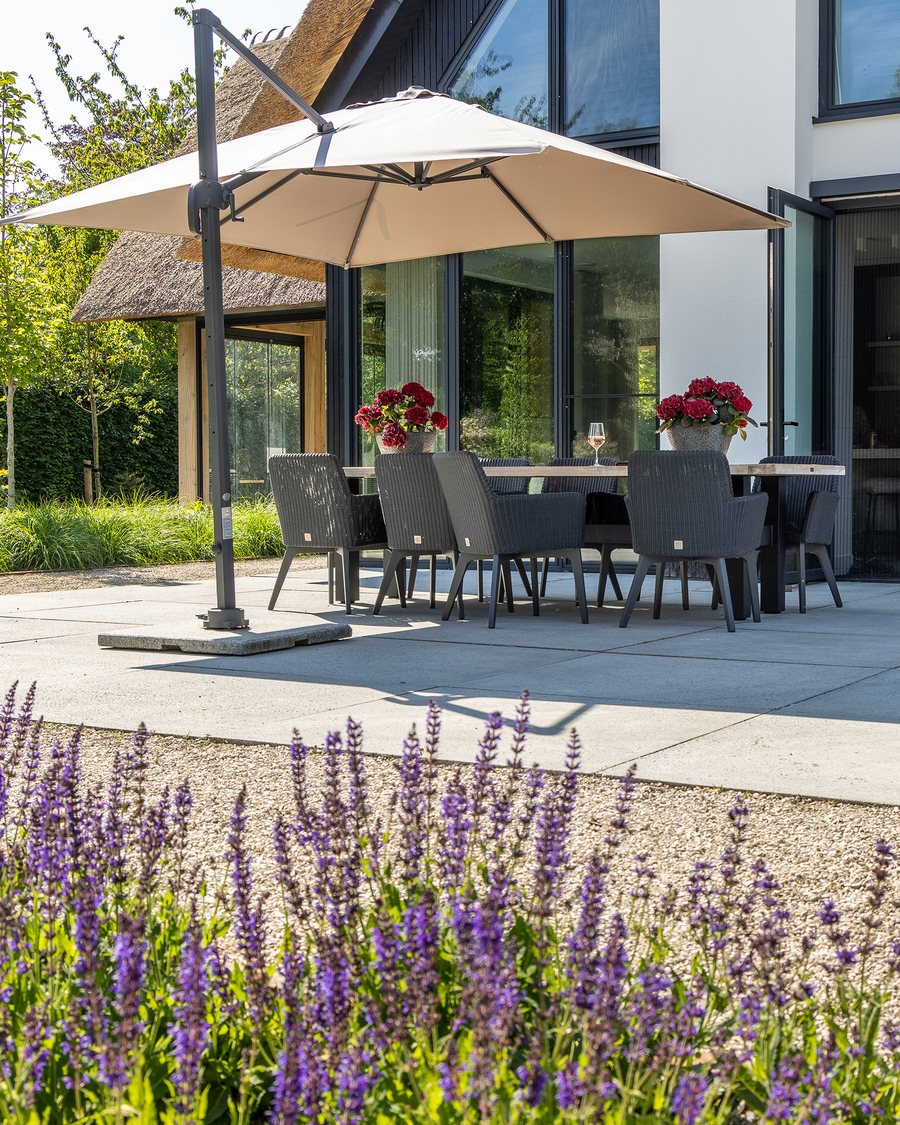 Terras met eettafel en parasol tussen lavendel