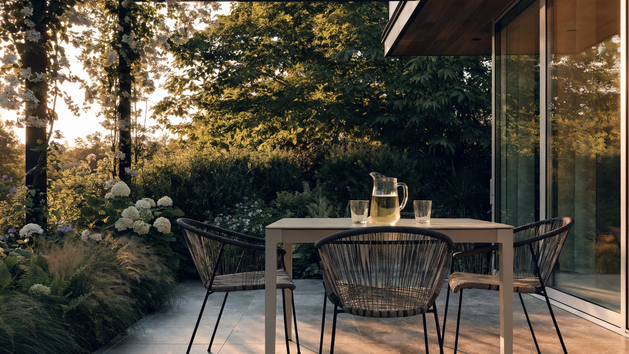 Terras met grootformaat tegels onder een overkapping, in avondlicht